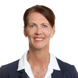 Frau mit braunen kurzen Haaren, weißem Hemd und dunklem Jackett schaut in die Kamera.
