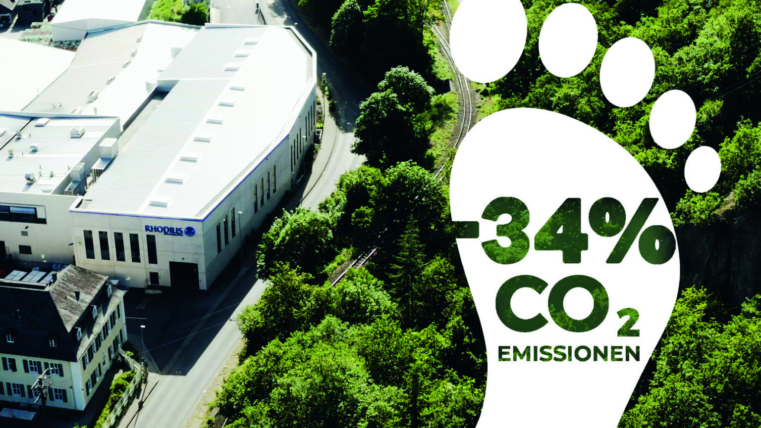 Ansicht auf das Firmengeländer von RHODIUS von oben. Am rechten Bildrand ist die Grafik von einem weißen Fußabdruck mit der Beschriftung –34% CO2 Emissionen eingefügt.